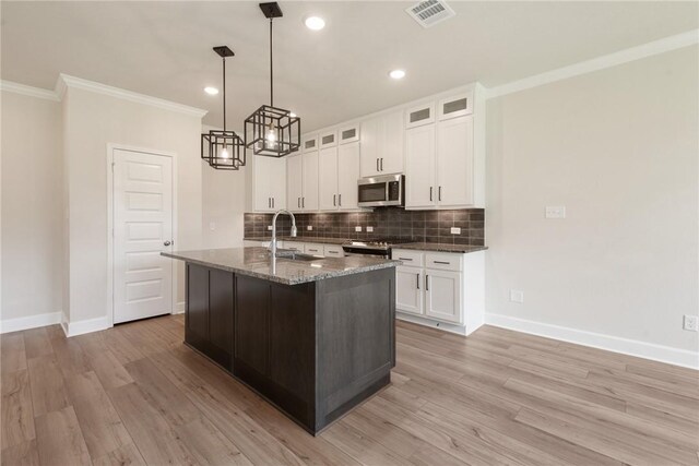 kitchen featuring white cabinets, light hardwood / wood-style floors, stainless steel appliances, and an island with sink