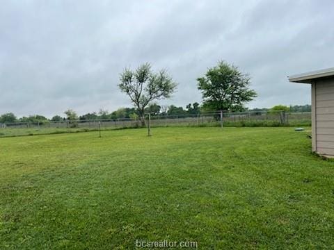 view of yard with fence and a rural view