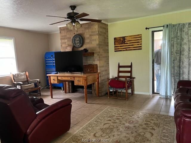 tiled living room with a textured ceiling, a ceiling fan, and crown molding