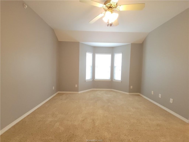 spare room featuring vaulted ceiling, light colored carpet, and ceiling fan