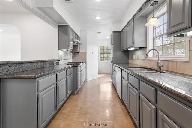 kitchen featuring decorative backsplash, gray cabinets, dark stone countertops, and sink