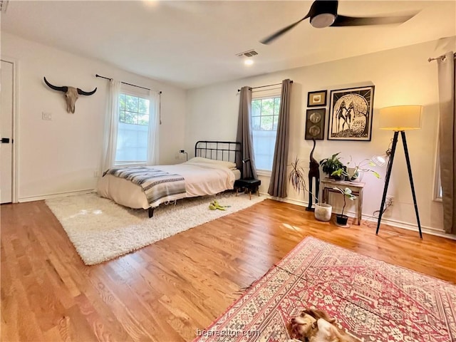 bedroom with multiple windows, hardwood / wood-style floors, and ceiling fan