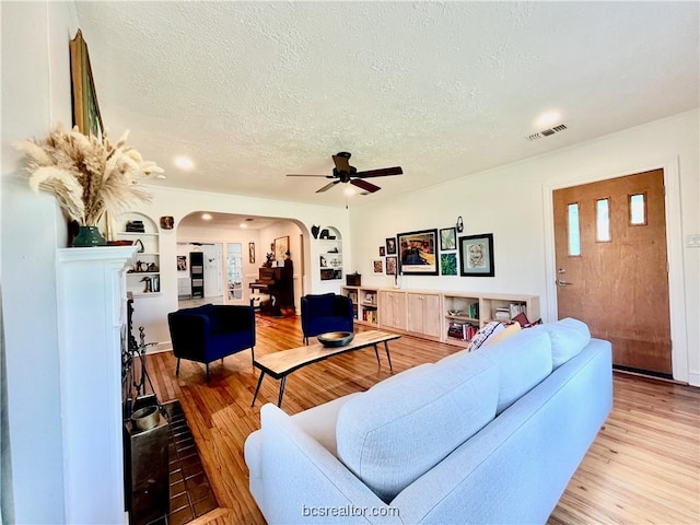 living room featuring ceiling fan, light hardwood / wood-style floors, and a textured ceiling