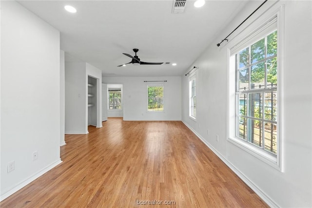 unfurnished living room with ceiling fan, a wealth of natural light, and light hardwood / wood-style flooring