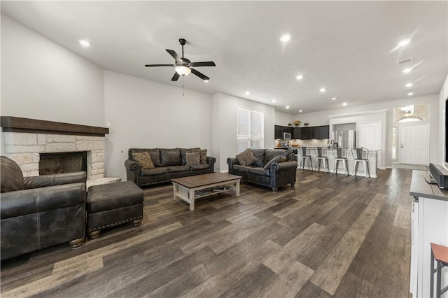 living room featuring ceiling fan, a fireplace, and dark hardwood / wood-style floors