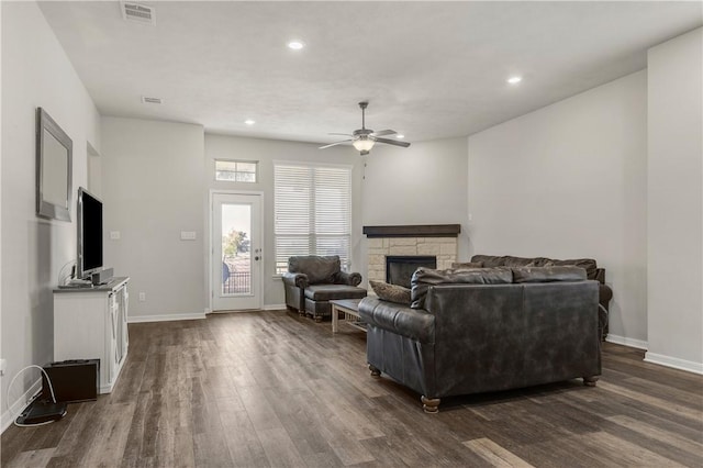 living room featuring a fireplace, ceiling fan, and dark wood-type flooring