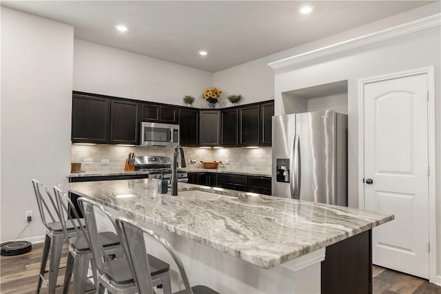 kitchen featuring appliances with stainless steel finishes, a breakfast bar, dark wood-type flooring, sink, and a center island with sink