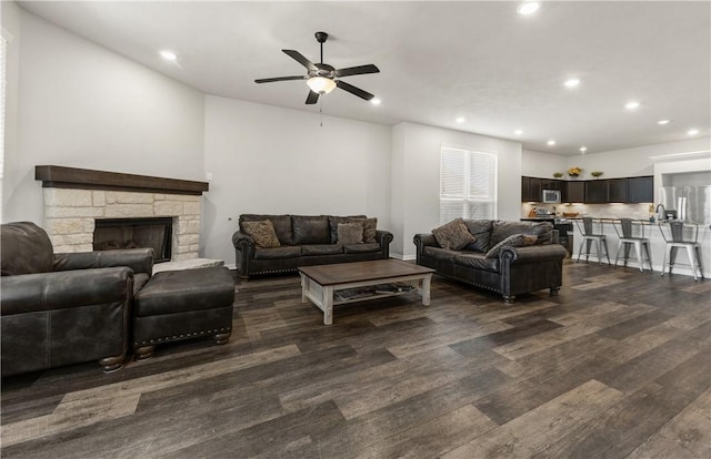 living room with ceiling fan, dark hardwood / wood-style flooring, and a fireplace