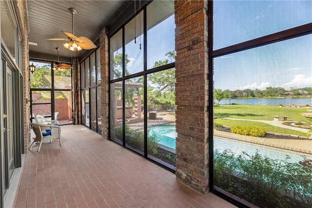 unfurnished sunroom with ceiling fan, a water view, and a healthy amount of sunlight