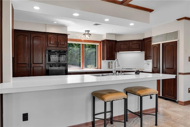 kitchen featuring light countertops, a breakfast bar area, visible vents, and paneled refrigerator