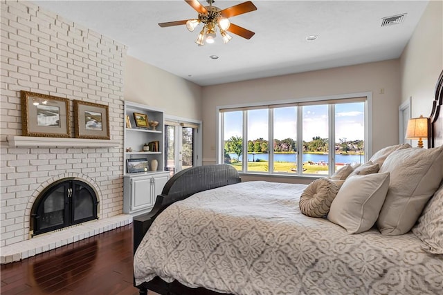 bedroom featuring visible vents, dark wood finished floors, a ceiling fan, a water view, and access to exterior