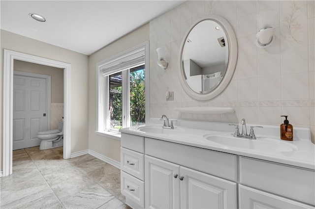 full bathroom with double vanity, tile walls, and a sink
