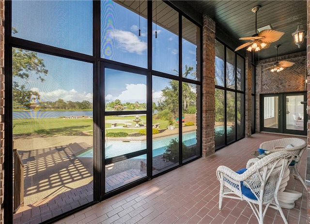 unfurnished sunroom with a water view, french doors, and a ceiling fan