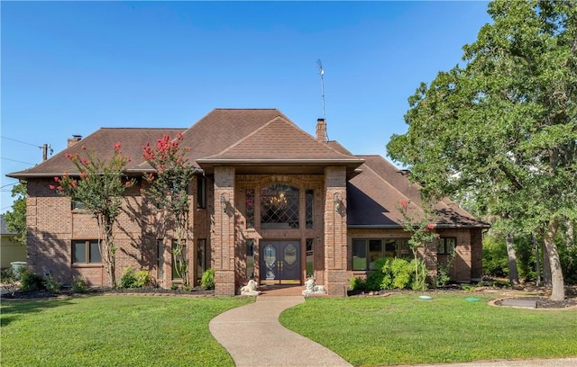 view of front facade featuring a chimney, a front lawn, and brick siding