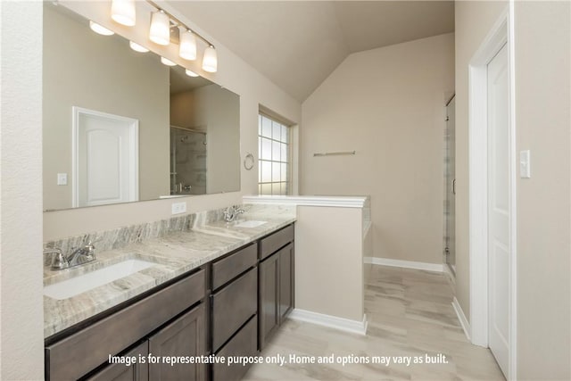 bathroom with vanity, a shower with shower door, and vaulted ceiling