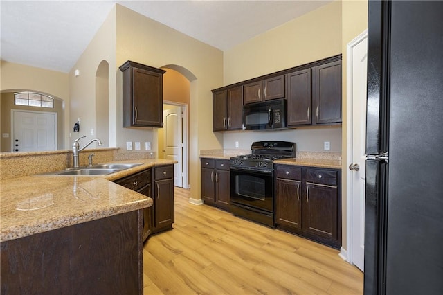 kitchen featuring light stone countertops, light hardwood / wood-style floors, black appliances, dark brown cabinets, and sink