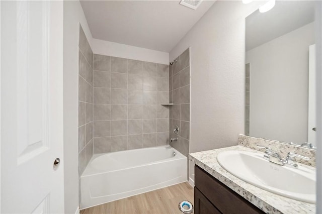 bathroom with vanity, tiled shower / bath, and hardwood / wood-style floors