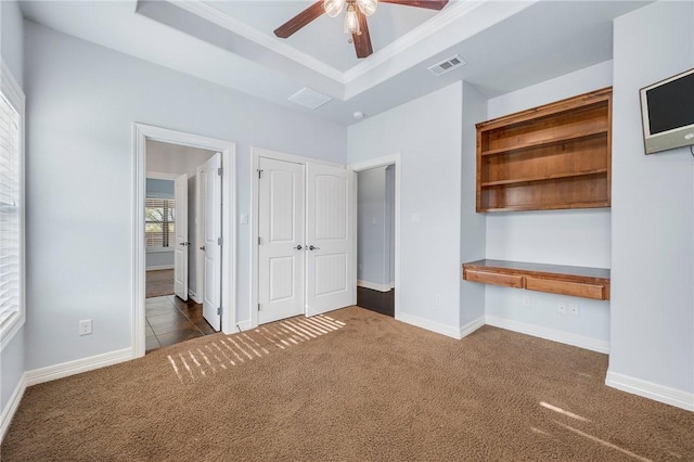 5398 Prairie Dawn Trl, College Station, TX 77845 - unfurnished bedroom featuring visible vents, built in study area, baseboards, a tray ceiling, and carpet