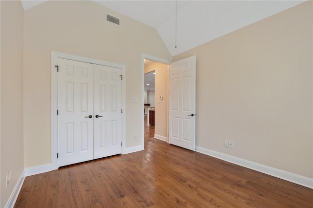 unfurnished bedroom featuring a closet, hardwood / wood-style floors, and lofted ceiling