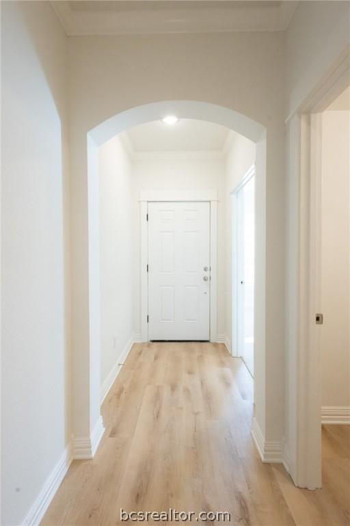 corridor with crown molding and light hardwood / wood-style flooring