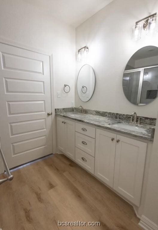 bathroom with hardwood / wood-style flooring, vanity, and an enclosed shower