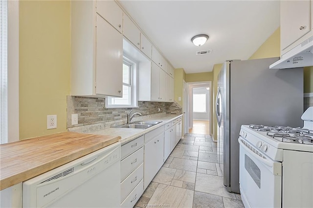 kitchen featuring white appliances, backsplash, white cabinetry, and sink