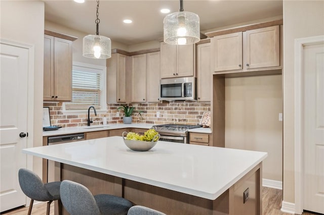 kitchen with pendant lighting, sink, stainless steel appliances, and a kitchen island