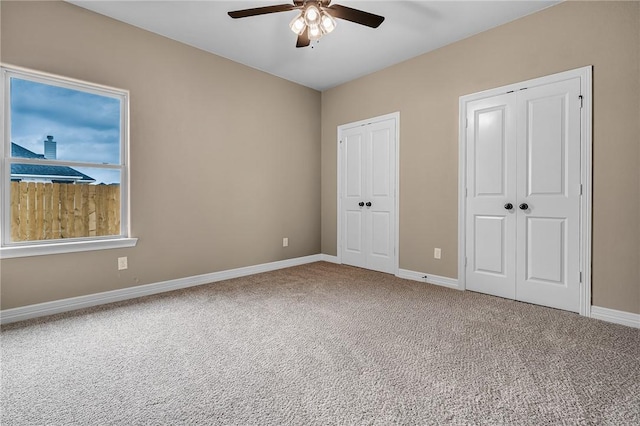 unfurnished bedroom with multiple closets, carpet, and ceiling fan