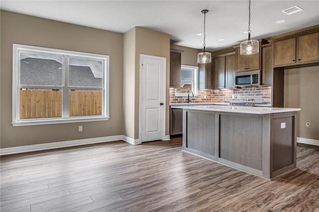 kitchen with hanging light fixtures, stainless steel appliances, a healthy amount of sunlight, and a kitchen island