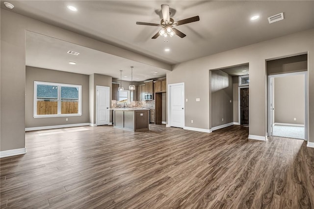 unfurnished living room featuring dark wood-type flooring and ceiling fan