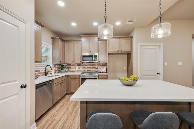 kitchen featuring sink, stainless steel appliances, decorative backsplash, decorative light fixtures, and light brown cabinets