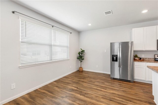 kitchen with white cabinets, stainless steel fridge, dark hardwood / wood-style flooring, and light stone counters