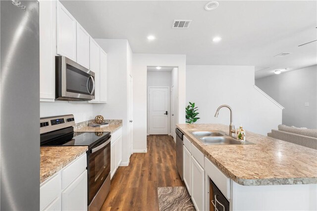 kitchen featuring appliances with stainless steel finishes, a kitchen island with sink, dark wood-type flooring, sink, and white cabinets