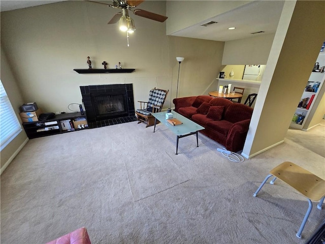 carpeted living room with a tiled fireplace and ceiling fan