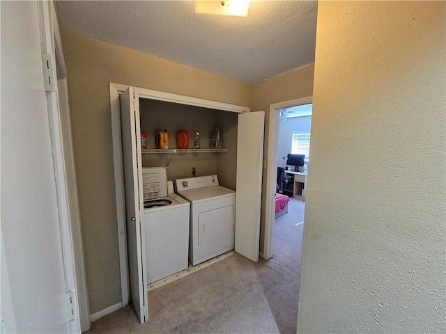 clothes washing area with light colored carpet, a textured ceiling, and washing machine and clothes dryer