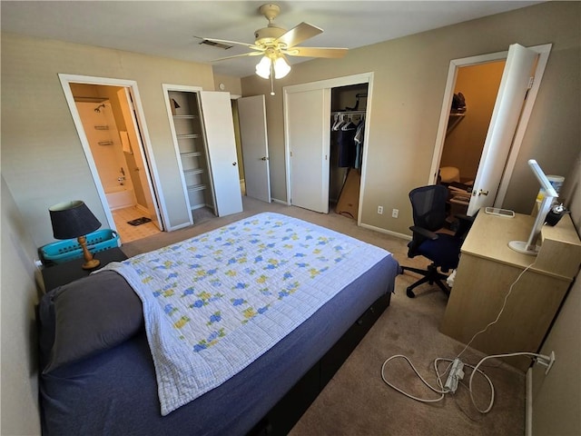 carpeted bedroom featuring ensuite bath, ceiling fan, and two closets