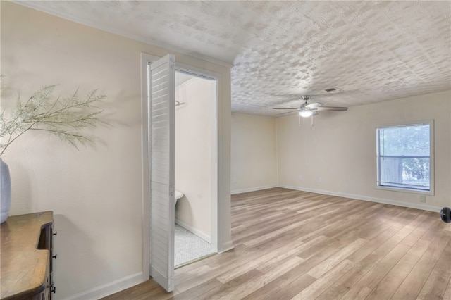 empty room with ceiling fan, a textured ceiling, and light hardwood / wood-style flooring