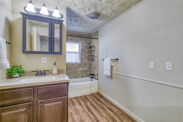 bathroom with crown molding, wood-type flooring, a textured ceiling, vanity, and tiled shower / bath