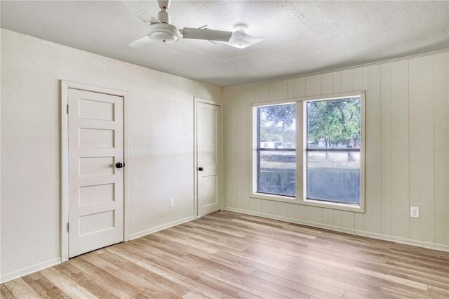 unfurnished room with a textured ceiling, light hardwood / wood-style floors, and ceiling fan