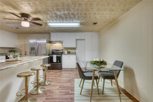 kitchen with electric stove, decorative backsplash, white cabinets, and light wood-type flooring