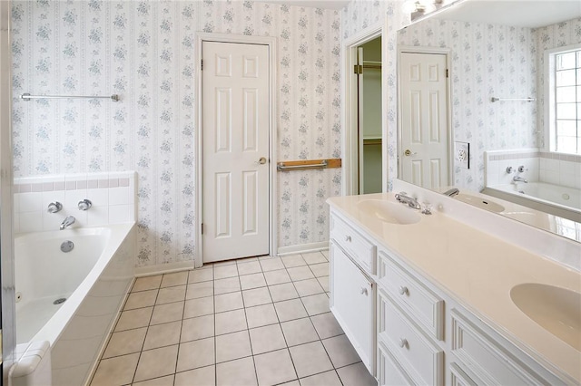 bathroom with tile patterned flooring, vanity, and tiled bath