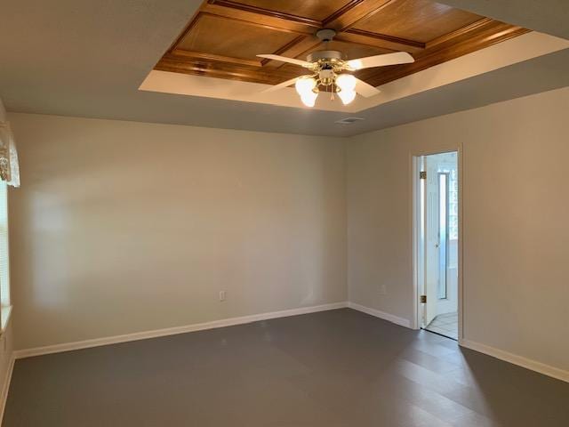 empty room with a tray ceiling, ceiling fan, crown molding, and wood ceiling