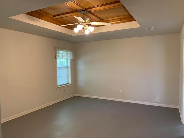 unfurnished room featuring ceiling fan, a raised ceiling, and wood ceiling