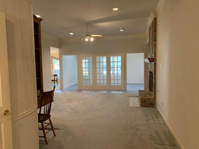 unfurnished living room with ceiling fan, carpet floors, ornamental molding, and a brick fireplace