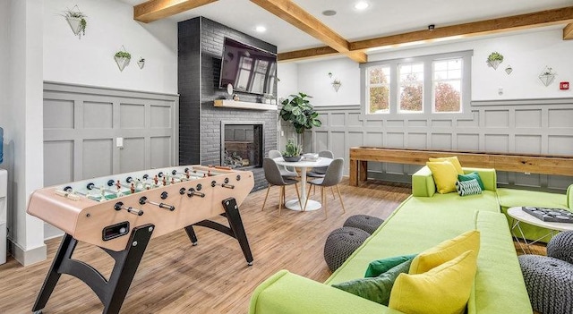 1725 Harvey Mitchell Pkwy S Unit 2433, College Station, TX 77840 - playroom with a decorative wall, beam ceiling, a brick fireplace, wainscoting, and wood finished floors