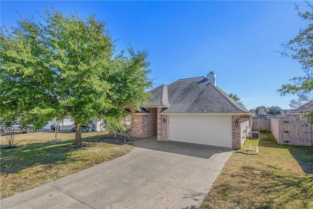 view of front of property featuring an attached garage, central AC, brick siding, fence, and a front yard