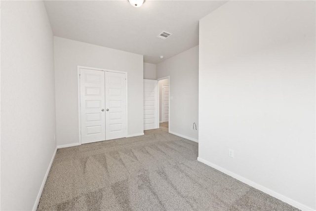 unfurnished bedroom with a closet and light colored carpet