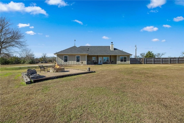 rear view of property featuring a yard and an outdoor fire pit