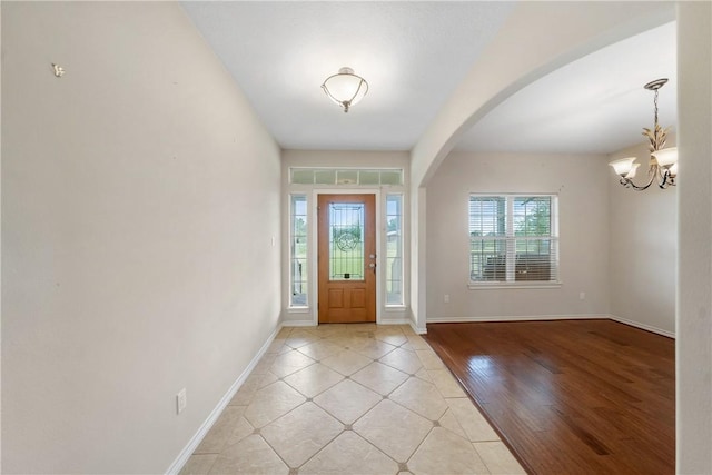 32287 Rochen Rd, Waller, TX 77484 - entrance foyer featuring arched walkways, baseboards, a chandelier, and light tile patterned floors