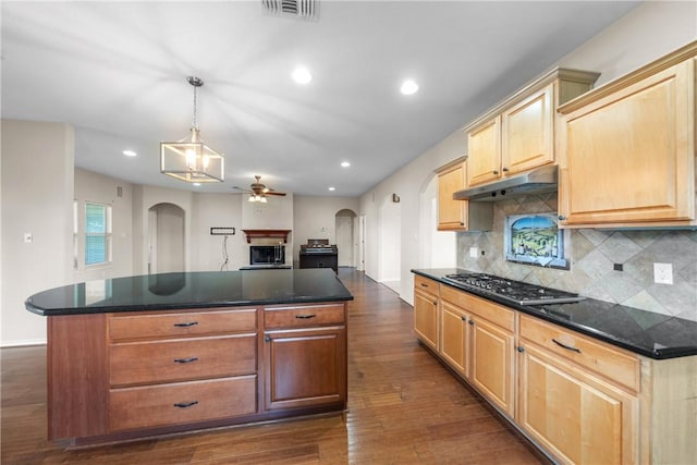 32287 Rochen Rd, Waller, TX 77484 - kitchen featuring under cabinet range hood, arched walkways, dark countertops, ceiling fan, and stainless steel gas cooktop